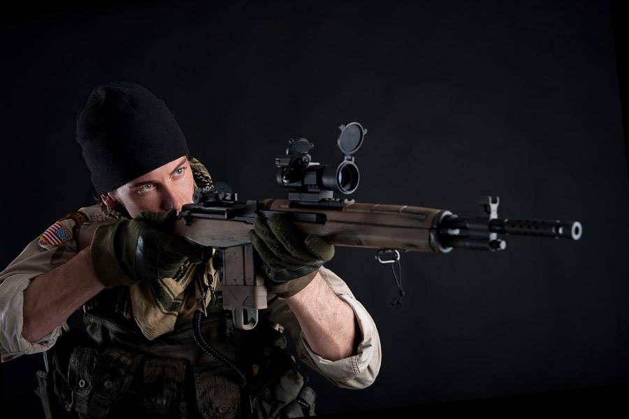 Soldier with rifle against black background.