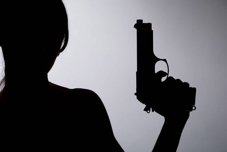 Silhouette of a woman with a gun on a gray background